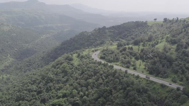 Aerial Shot of Cars Driving Through Lush Green Sahyadri Hills, Wide to Close
