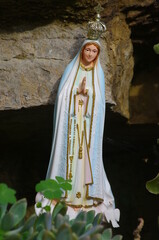 Statue of Mary is sitting on a rock