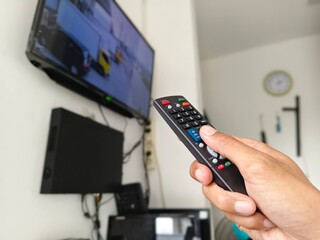closeup photo of a hand holding a TV remote