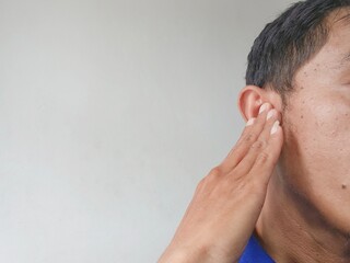 Man plugging ear with finger to block noise, expressing discomfort, irritation, or ignoring sound, closeup on white background
