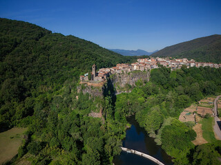 Medieval village of Castellfollit de la Roca perched atop dramatic basalt cliffs above the Fluvià river in Garrotxa, Catalonia; concept: geology, heritage.