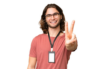 Young handsome man with ID card over isolated background smiling and showing victory sign