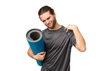 Young sport man going to yoga classes while holding a mat over isolated background suffering from pain in shoulder for having made an effort