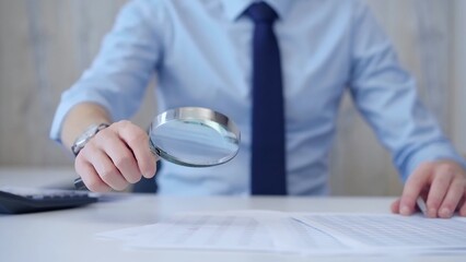 Businessman is carefully examining financial documents with a magnifying glass, highlighting the importance of thorough analysis in business. Audit and taxes