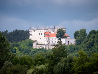 Castle of Slovensk&aacute; Ľupča in central Slovakia, historical fortress on a forested hilltop under dramatic sky, view from a distance.