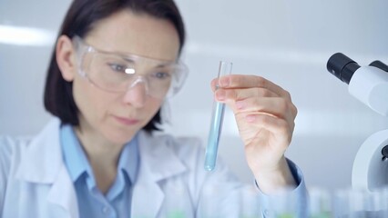 Scientist female researcher with protective glasses examining la