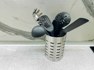 This sleek stainless steel utensil holder effectively organizes your stylish black kitchen...