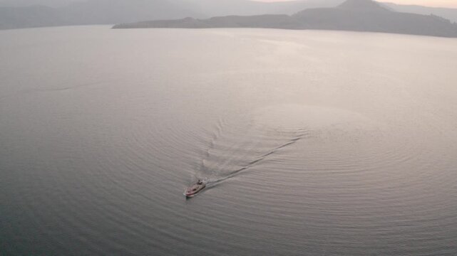 boat sailing in river hills in background sunset