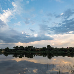 Obraz premium very beautiful sunset with water. summer evening landscape with reflection of clouds in water. setting sun on horizon. summer landscape with lake. reflection of trees in water. sunrise on river
