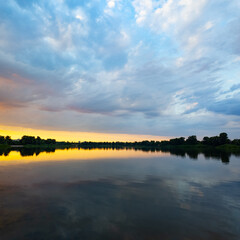 Obraz premium very beautiful sunset with water. summer evening landscape with reflection of clouds in water. setting sun on horizon. summer landscape with lake. reflection of trees in water. sunrise on river