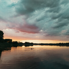 Obraz premium very beautiful sunset with water. summer evening landscape with reflection of clouds in water. setting sun on horizon. summer landscape with lake. reflection of trees in water. sunrise on river
