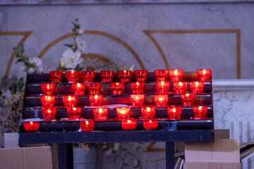 Red prayer candles in church with flowers in background, France, Corsica, Cargèse, 15 June 2025