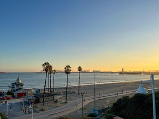 A beach with palm trees and a sunset in the background