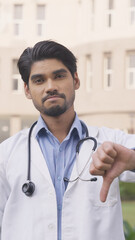Vertical Photo of Sad Indian Doctor Showing Thumbs Down
