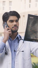 Vertical Photo of Indian Doctor Looking at X Ray Report and Talking on Phone
