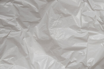 Obraz premium Crumpled white plastic film close up, texture of packaging material, plain polyethylene background with highlights and folds