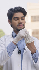 Vertical Photo of Indian Doctor Removing Surgical Gloves