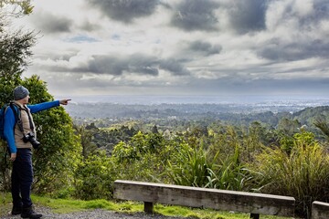 A photographer points towards the landscape from a scenic overlook in Auckland, New Zealand. He is...