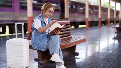 Older Asian Woman Patiently Reading Book Waiting Train Travel Adventure Journey At Station Platform