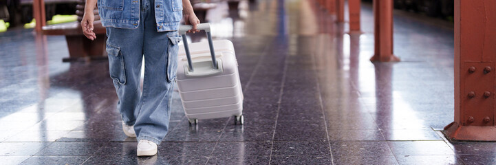 Adult traveler pulling white suitcase walking train station platform ready for journey
