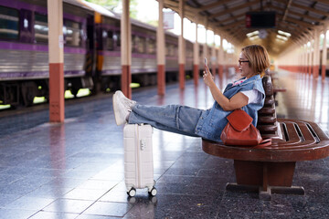Older Asian woman senior traveler use smartphone wait train station platform relax independent journey leisure lifestyle connectivity comfortable peaceful moment tourism transportation
