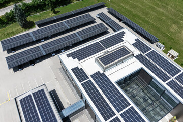 Aerial view of building with solar panels on a roof and parking space with solar canopies