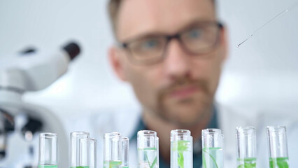 Man researcher with safety glasses is working with lab tubes using a pipette in laboratory, close-up of lab equipment. Science and medicine