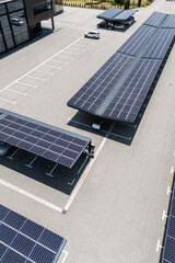 Aerial view of building with solar panels on a roof and parking space with solar canopies