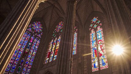 Stained glass windows in gothic cathedral illuminated by sunlight, revealing vibrant colors, sacred beauty, and cultural architectural heritage - Powered by Adobe