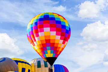 Naklejka premium Colorful hot air balloon flying over blue sky with white clouds 