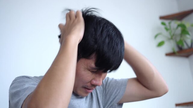 Asian Man Scratching His Scalp and Itching His Hair Struggling with Dandruff and Scalp Irritation, Seeking Relief from Flaky Skin and Discomfort