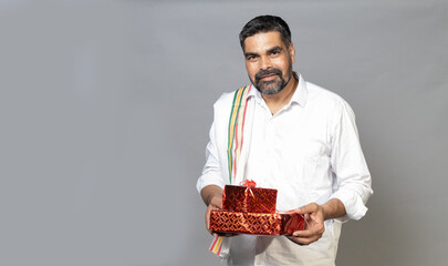 Happy indian man in ethnic wear holding Gift box towards the camera