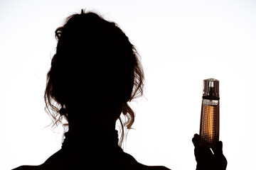 Silhouette of Woman Holding Elegant Perfume Bottle with Light