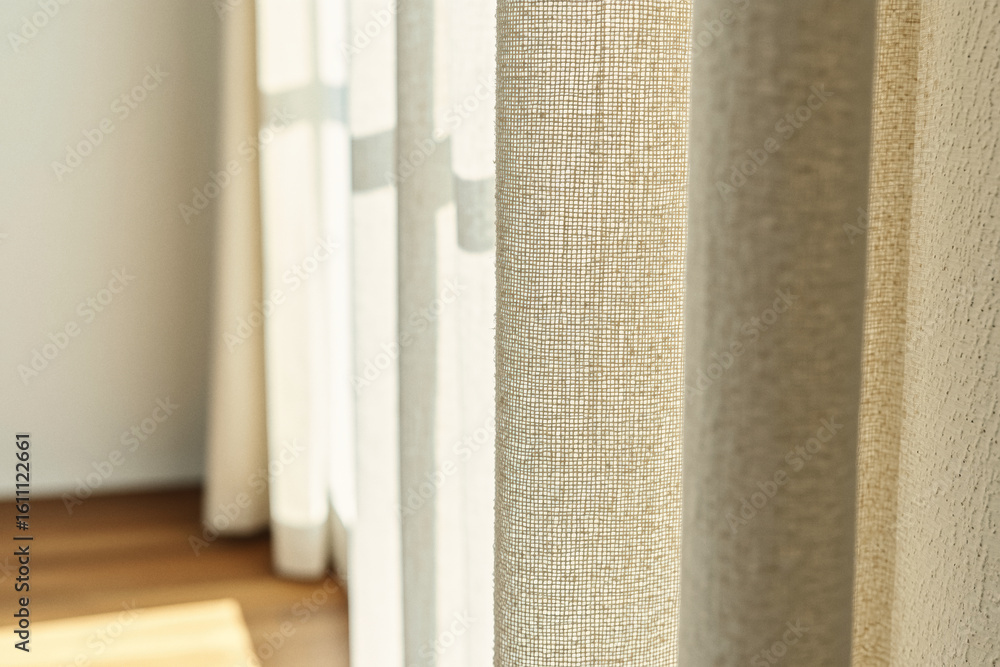 Poster soft, textured linen curtains partially obscure a bright window, creating a warm and inviting atmosp