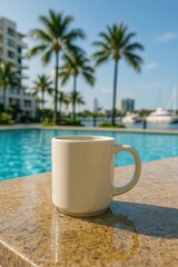 Fototapeta premium White ceramic coffee mug on a granite table by a swimming pool with palm trees and yachts in the background on a sunny day. Relaxing tropical vacation scene.