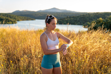 Young athlete checking smartwatch during summer workout by the lake