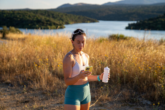 Young woman checking her phone while hiking in nature