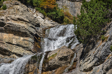 Naklejka premium a small waterfall along the road road that goes up the the Stelvio Pass inside the Stelvio National Park on the Lombard side, Sondrio, Italy