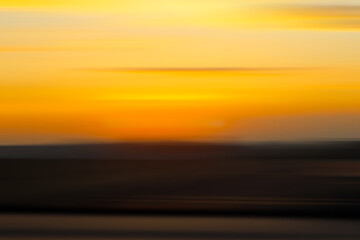 Obraz premium Abstract blurred background of a dawn breaks with warm tones of orange and yellow. Ideal for use in designs, overlays, or nature-themed projects.