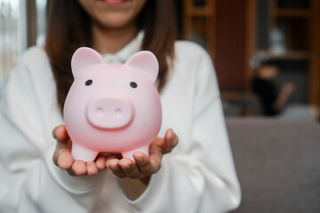 Close-up of a woman holding a pink piggy bank, representing savings and financial planning in a...