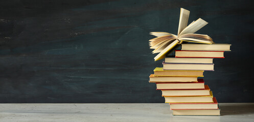 Heap of multicolored books on dark grungy background. Negative space with large free space for text..