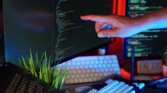Developer hand code screen home office computer setup with colorful ambient lighting Programmer pointing at computer monitor 