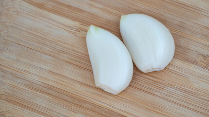 Two Fresh Onion Cloves on Wooden Cutting Board Close-Up