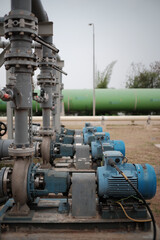 Naklejka premium Industrial landscape displaying a series of robust water pumps and intricate pipeline systems conveying vital resources in infrastructure settings featuring heavy machinery and valve mechanisms
