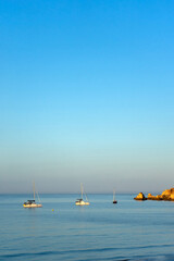 Aerial view of boats floating on calm waters at Praia do Alem&atilde;o, Portim&atilde;o, Algarve, during a peaceful morning with soft sunlight.