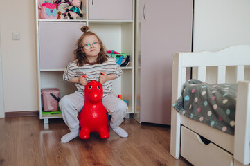 Joyful young girl with Down syndrome smiling and playing happily in her brightly lit, colorful bedroom