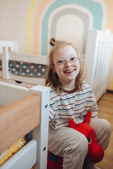 Joyful young girl with Down syndrome smiling and playing happily in her brightly lit, colorful bedroom
