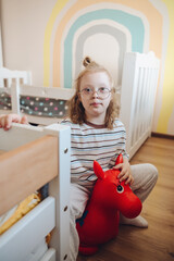 Joyful young girl with Down syndrome smiling and playing happily in her brightly lit, colorful bedroom
