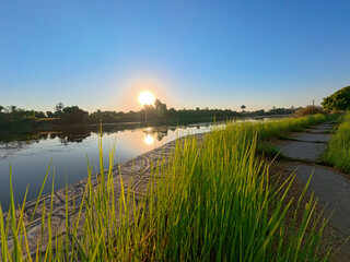 Panoramic landscape view across nile river to luxor west bank with sunrise and riverside footpath