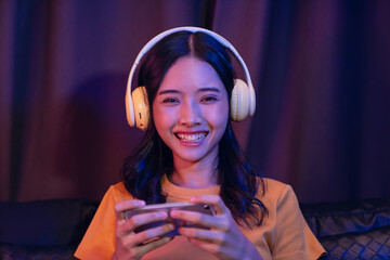Excited Young Asian girl playing an online game on a smartphone on the sofa in the living room.